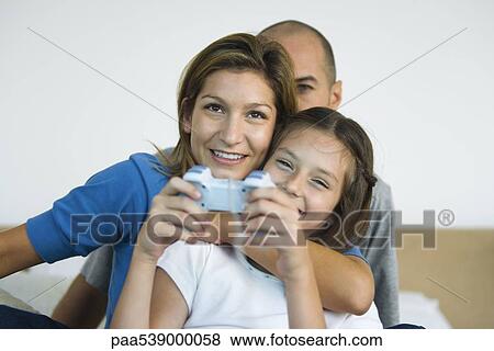 Girl playing video game, parents watching View Large Photo Image Stock Photo - Girl playing video game, parents watching. Fotosearch