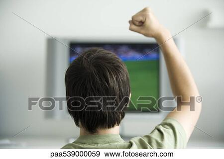 Male watching television, one fist raised in air, rear view View Large Photo Image Stock Photo - Male watching television, one fist raised in air, rear view. Fotosearch