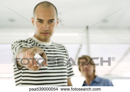 Picture - Man holding out wireless remote control, focus on foreground. Fotosearch