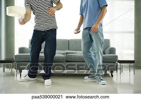Stock Image - Two men playing video game with wireless controllers, cropped. Fotosearch