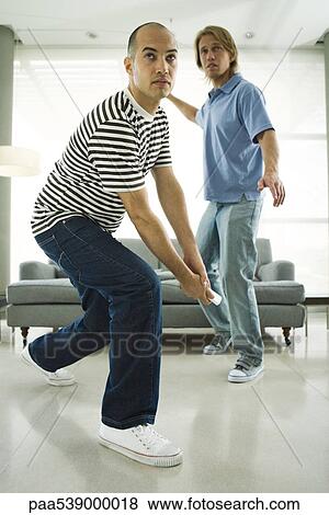 Stock Photo - Two men playing video game with wireless controllers. Fotosearch