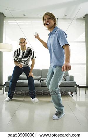 Two men playing video games with wireless controllers View Large Photo Image Stock Image - Two men playing video games with wireless controllers. Fotosearch
