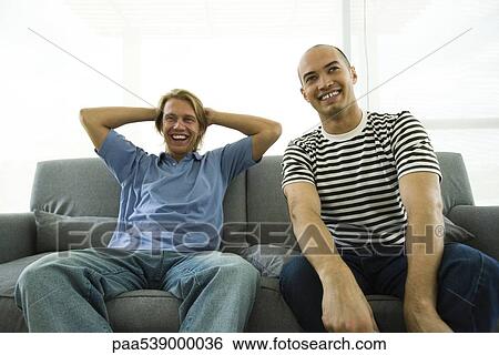 Two men sitting on sofa, laughing View Large Photo Image Stock Photograph - Two men sitting on sofa, laughing. Fotosearch