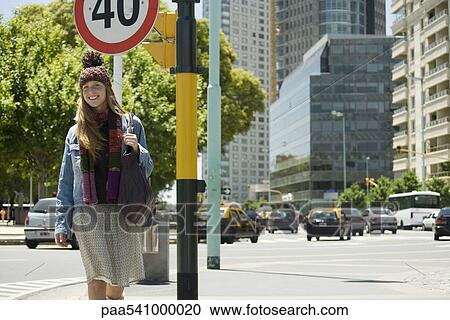 Trendy young woman walking along city street View Large Photo Image Stock Image - Trendy young woman walking along city street. Fotosearch