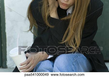Young woman leaning on elbow, holding cup, cropped view View Large Photo Image Stock Photo - Young woman leaning on elbow, holding cup, cropped view. Fotosearch