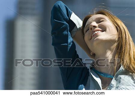 Young woman outdoors, smiling with one hand behind head and eyes closed View Large Photo Image Stock Image - Young woman outdoors, smiling with one hand behind head and eyes closed. Fotosearch