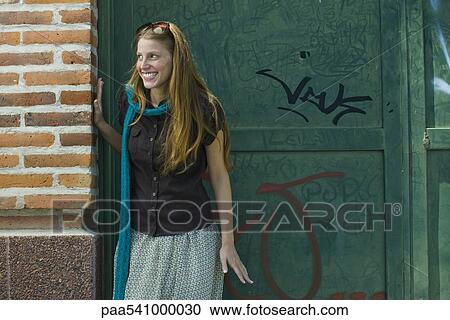 Young woman standing in alley, looking away, smiling View Large Photo Image Stock Image - Young woman standing in alley, looking away, smiling. Fotosearch