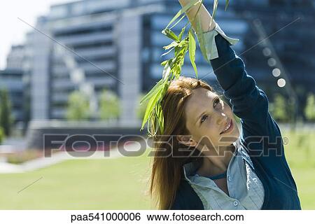 Young woman standing outdoors, touching branch, looking away View Large Photo Image Stock Photograph - Young woman standing outdoors, touching branch, looking away. Fotosearch