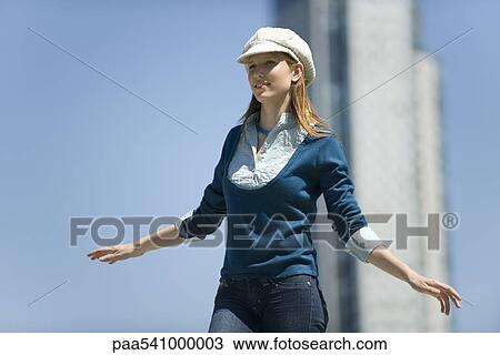 Young woman wearing trendy hat, standing outdoors with arms out View Large Photo Image Stock Image - Young woman wearing trendy hat, standing outdoors with arms out. Fotosearch