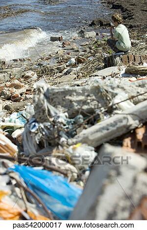 Boy crouching on polluted shore, wearing pollution mask View Large Photo Image Stock Photo - Boy crouching on polluted shore, wearing pollution mask. Fotosearch