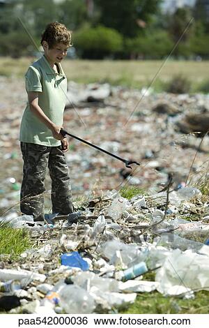 Boy picking up garbage with grabbing device View Large Photo Image Stock Photograph - Boy picking up garbage with grabbing device. Fotosearch