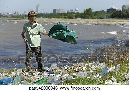 Boy picking up litter on shore, holding garbage bag and magnetic device View Large Photo Image Stock Image - Boy picking up litter on shore, holding garbage bag and magnetic device. Fotosearch