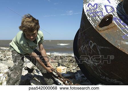Boy pulling rusty chain on polluted shore View Large Photo Image Stock Photo - Boy pulling rusty chain on polluted shore. Fotosearch