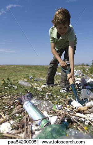 Boy shoveling trash in field View Large Photo Image Stock Image - Boy shoveling trash in field. Fotosearch