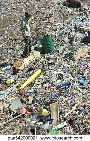 Boy standing in garbage dump, garbage can nearby, high angle view View Large Photo Image Stock Image - Boy standing in garbage dump, garbage can nearby, high angle view. Fotosearch