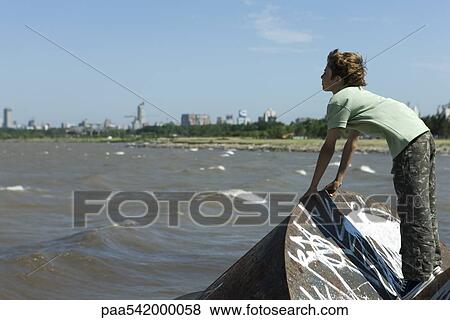 Boy standing on graffitied metal, looking at polluted bay View Large Photo Image Stock Photo - Boy standing on graffitied metal, looking at polluted bay. Fotosearch