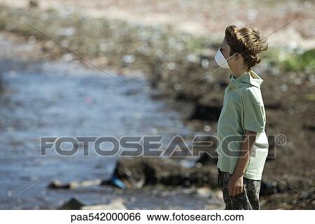 Boy wearing pollution mask, standing on polluted shore View Large Photo Image Stock Photograph - Boy wearing pollution mask, standing on polluted shore. Fotosearch