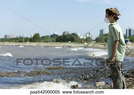 Boy wearing pollution mask, standing on polluted shore View Large Photo Image Stock Photography - Boy wearing pollution mask, standing on polluted shore. Fotosearch