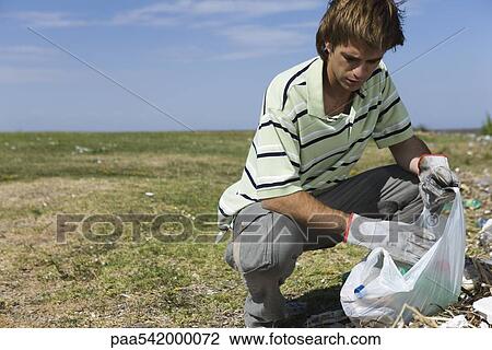 Male picking up trash in field View Large Photo Image Stock Image - Male picking up trash in field. Fotosearch