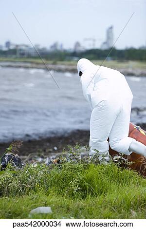 Person in protective suit cleaning up polluted shore View Large Photo Image Picture - Person in protective suit cleaning up polluted shore. Fotosearch