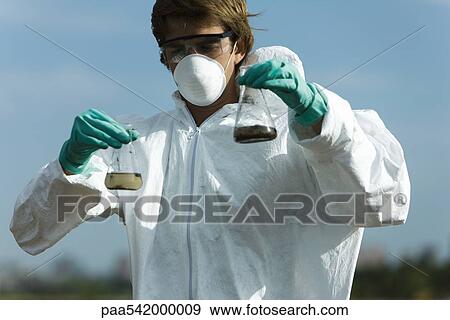 Person in protective suit holding flasks filled with polluted water View Large Photo Image Stock Photo - Person in protective suit holding flasks filled with polluted water. Fotosearch