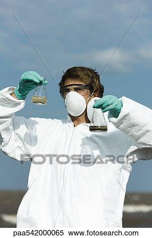 Person in protective suit holding flasks filled with polluted water View Large Photo Image Stock Photography - Person in protective suit holding flasks filled with polluted water. Fotosearch