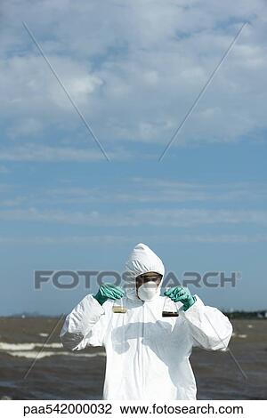 Person in protective suit holding up flasks filled with polluted water View Large Photo Image Stock Image - Person in protective suit holding up flasks filled with polluted water. Fotosearch
