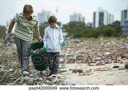 Stock Photo - Young male and boy collecting recyclable materials in garbage dump. Fotosearch