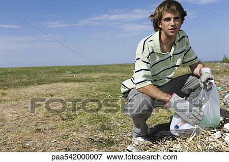 Young male cleaning up littered field, looking at camera View Large Photo Image Stock Photo - Young male cleaning up littered field, looking at camera. Fotosearch