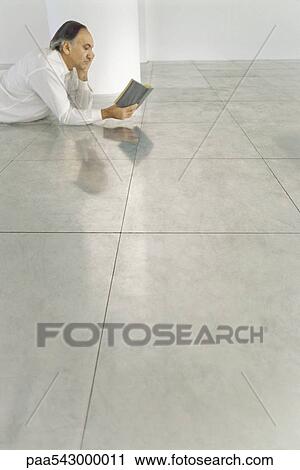 年長 人 うつ伏せに寝る 上に タイルを張られた 床 読む本 ストックイメージ Paa Fotosearch