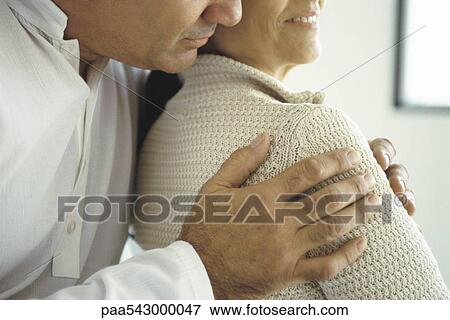 Stock Photo - Husband embracing wife from behind, cropped. Fotosearch