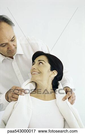 Husband placing jacket around wife's shoulders, wife looking up at him smiling View Large Photo Image Stock Photo - Husband placing jacket around wife's shoulders, wife looking up at him smiling. Fotosearch