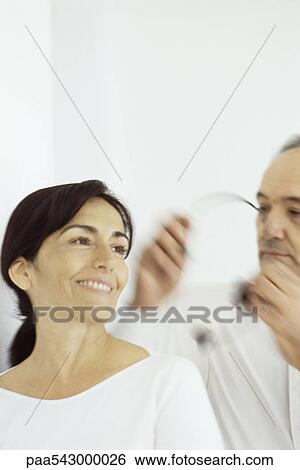 Stock Photograph - Man placing phone headset on woman's head. Fotosearch