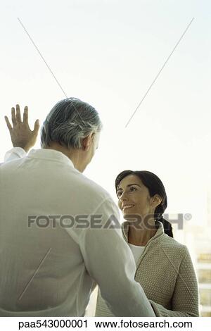 Stock Image - Mature couple, face to face standing by window. Fotosearch