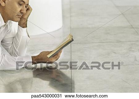 Senior man lying on tiled floor reading book View Large Photo Image Stock Image - Senior man lying on tiled floor reading book. Fotosearch