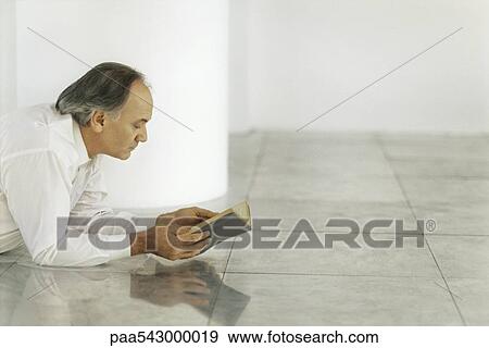 Senior man lying on tiled floor reading book View Large Photo Image Stock Photo - Senior man lying on tiled floor reading book. Fotosearch