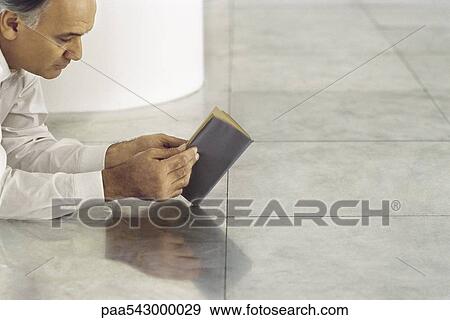 Senior man lying on tiled floor reading book View Large Photo Image Stock Photo - Senior man lying on tiled floor reading book. Fotosearch
