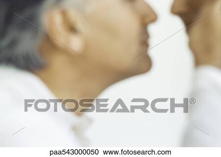 Stock Image - Senior man placing hand on wife's cheek, cropped. Fotosearch