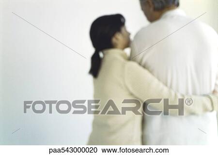 Stock Image - Woman embracing husband, displaying concern, rear view. Fotosearch