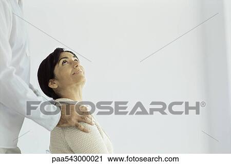 Stock Image - Woman sitting looking up at husband standing behind placing hands on her shoulders. Fotosearch