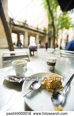 Coffee cup and half eaten pastry left on sidewalk cafe table View Large Photo Image Stock Photo - Coffee cup and half eaten pastry left on sidewalk cafe table. Fotosearch