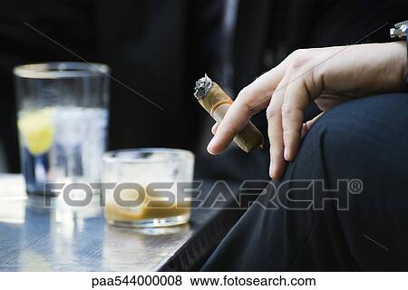 Man's hand on knee holding smoking cigar, close-up View Large Photo Image Stock Photo - Man's hand on knee holding smoking cigar, close-up. Fotosearch