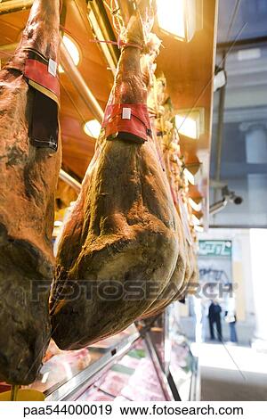 Stock Photo - Smoked pork legs hanging on display in butcher's shop. Fotosearch