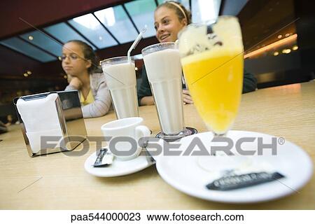 Teenage girls at cafe counter, milkshakes, glass of juice in foreground View Large Photo Image Stock Image - Teenage girls at cafe counter, milkshakes, glass of juice in foreground. Fotosearch
