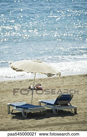 Stock Image - Parasol and lounge chairs on beach. Fotosearch
