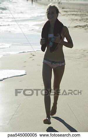 Stock Photography - Teen girl running on beach, backlit. Fotosearch