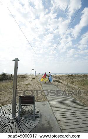 Stock Photo - Teen girls walking on boardwalk at beach. Fotosearch
