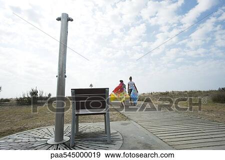 Stock Photo - Teen girls walking on boardwalk, carrying floats. Fotosearch