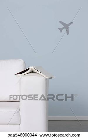 Book on arm of sofa, airplane in background View Large Photo Image Picture - Book on arm of sofa, airplane in background. Fotosearch