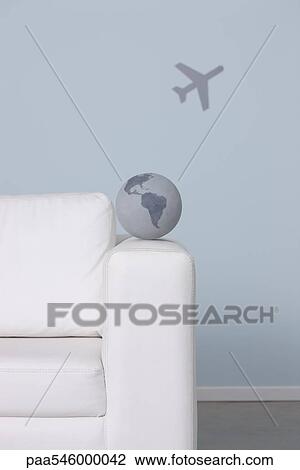 Globe on arm of sofa, airplane in background View Large Photo Image Stock Image - Globe on arm of sofa, airplane in background. Fotosearch